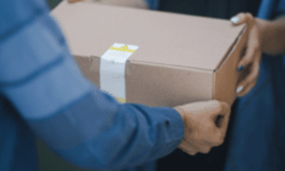 The hands of delivery personnel passing off a boxed package to a customer.