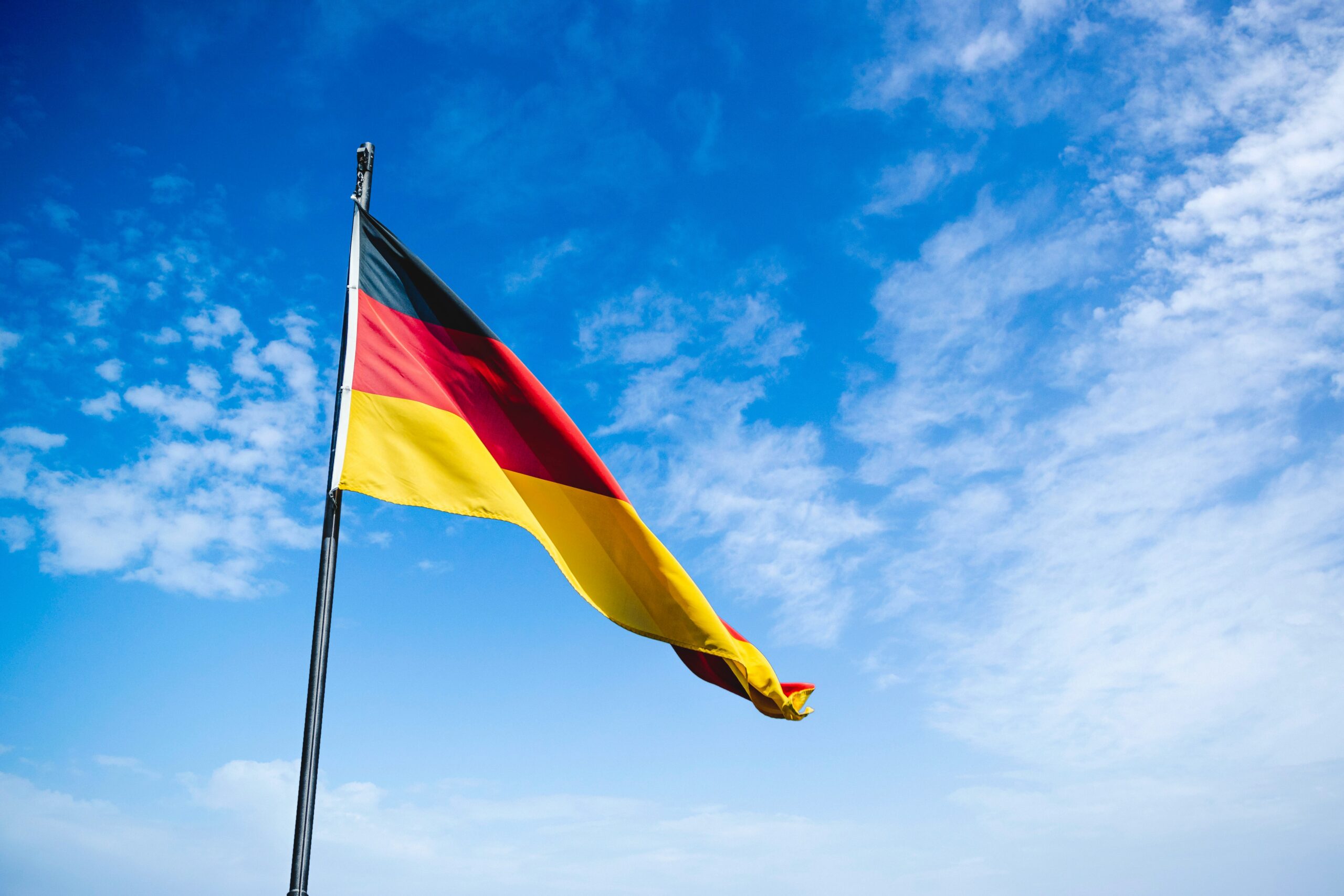 A Deutschland flag waving in the air on a flagpole.