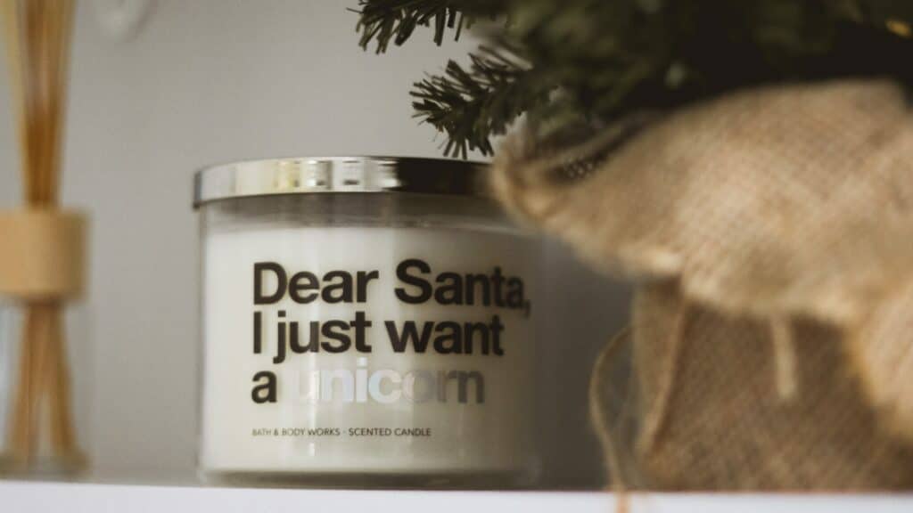A Bath and Body Works candle sits next to a pine tree. It says 'Dear Santa, I just want a unicorn'.