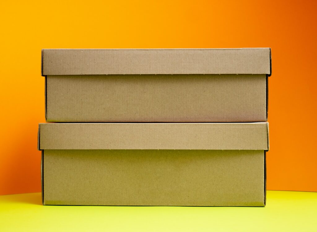 Brown boxes are stacked on a yellow table with an orange wall in the background.