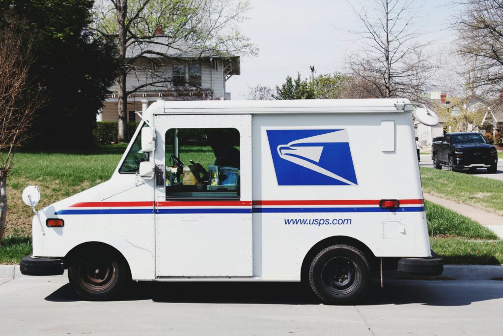USPS shipping/delivery van is parked in front of a house.