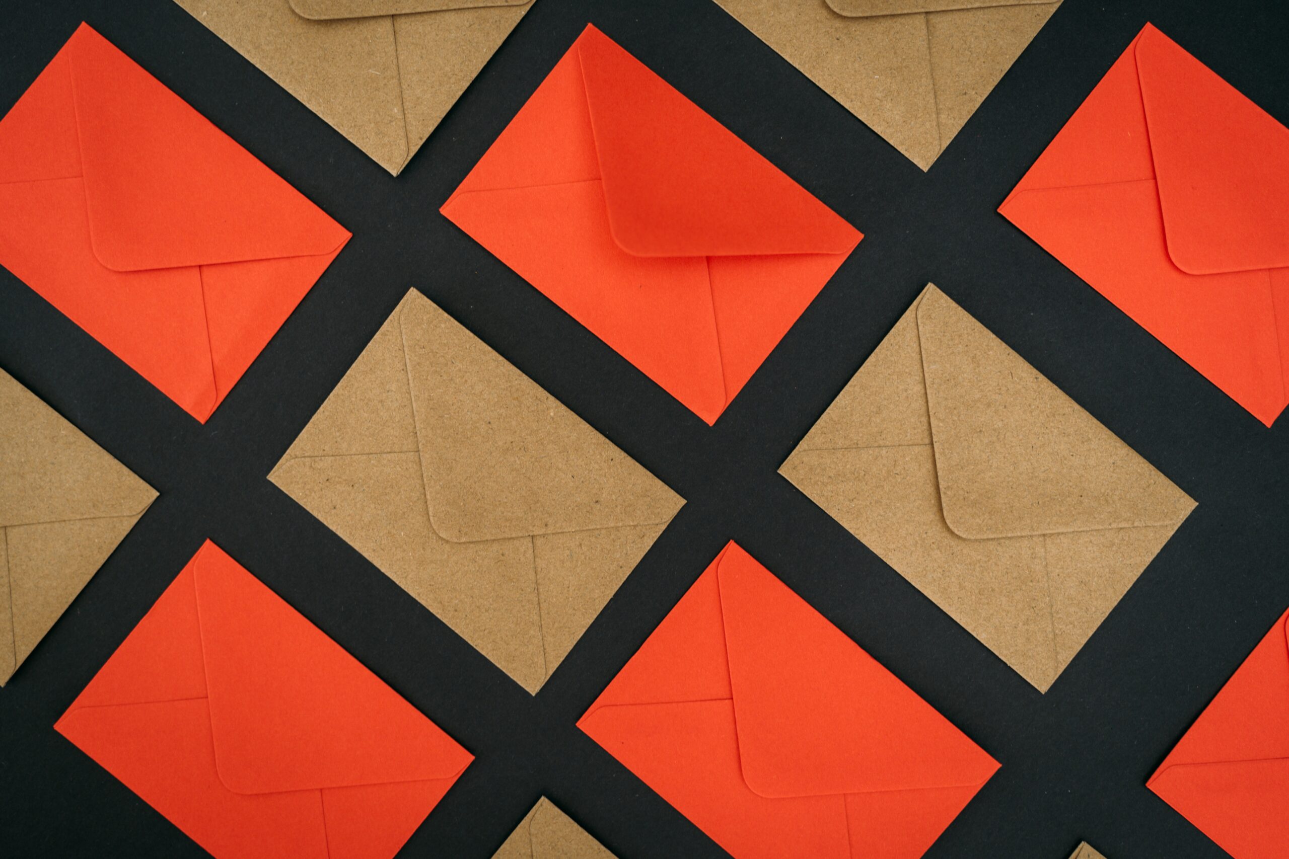 Red and brown card-size envelopes lay in a horizontal pattern above a black background.