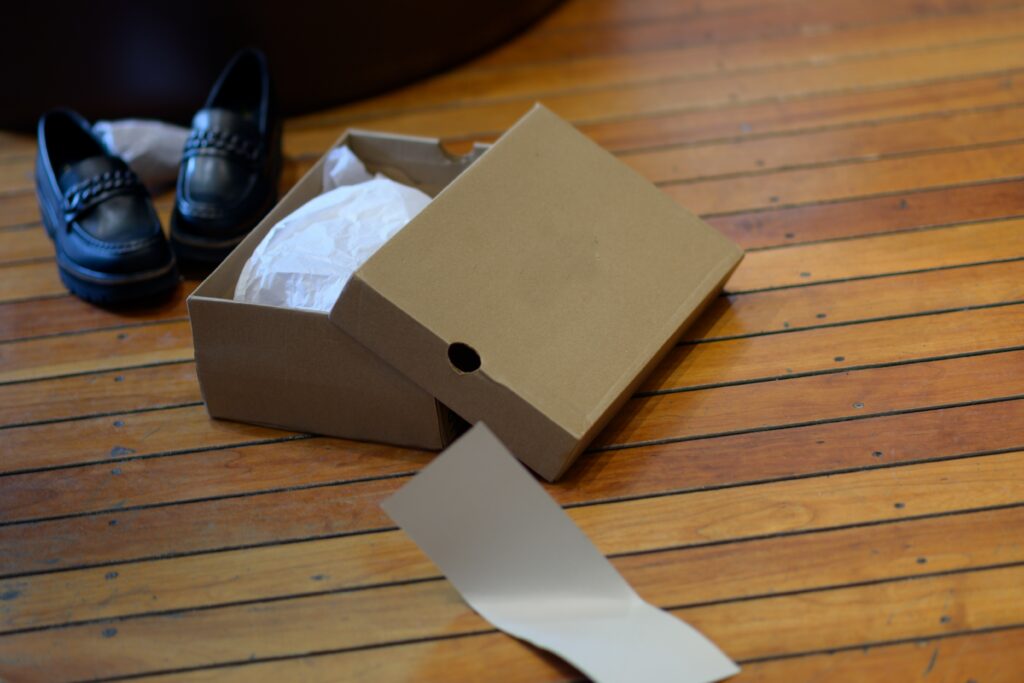 An opened shoe box is on the floor.
