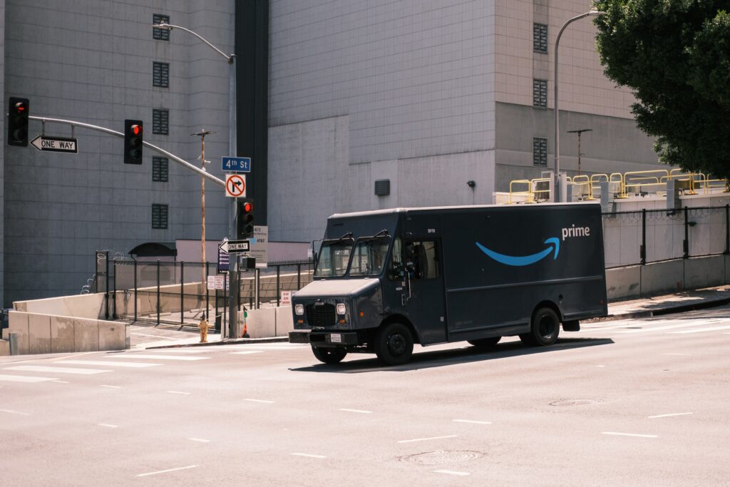 An Amazon delivery truck is driving around a city, connecting goods from a California warehouse to the recipient.
