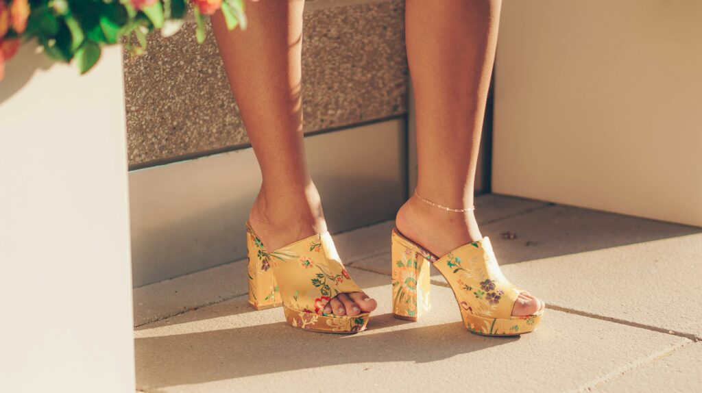 Womens feet, adorned in floral heels. Shows example of the type of products one may convert from US shoe size in EU.