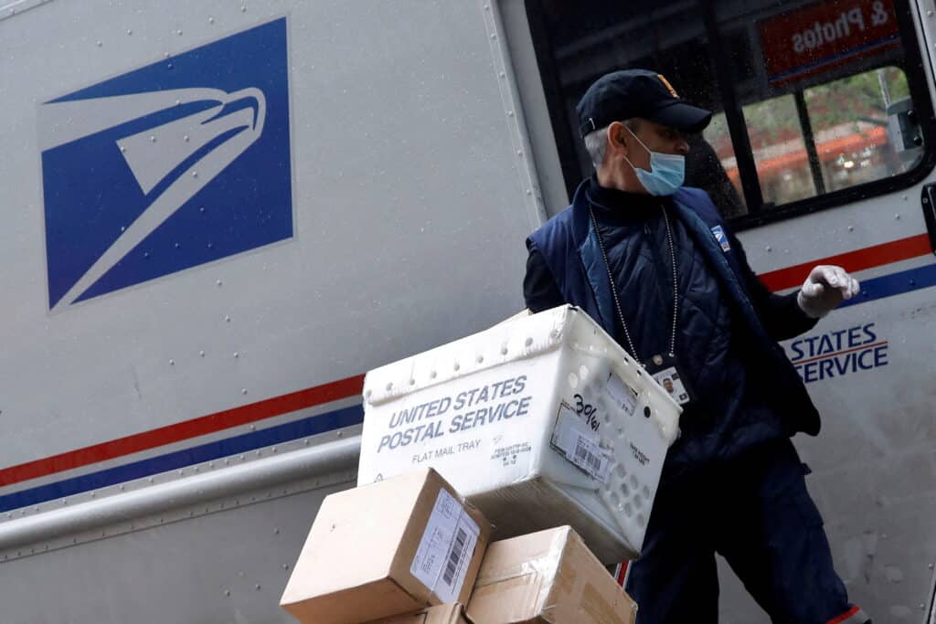 Un trabajador del Servicio Postal de los Estados Unidos (USPS) descarga paquetes de su camión en Manhattan durante el brote de la enfermedad del coronavirus (COVID-19) en la ciudad de Nueva York. 