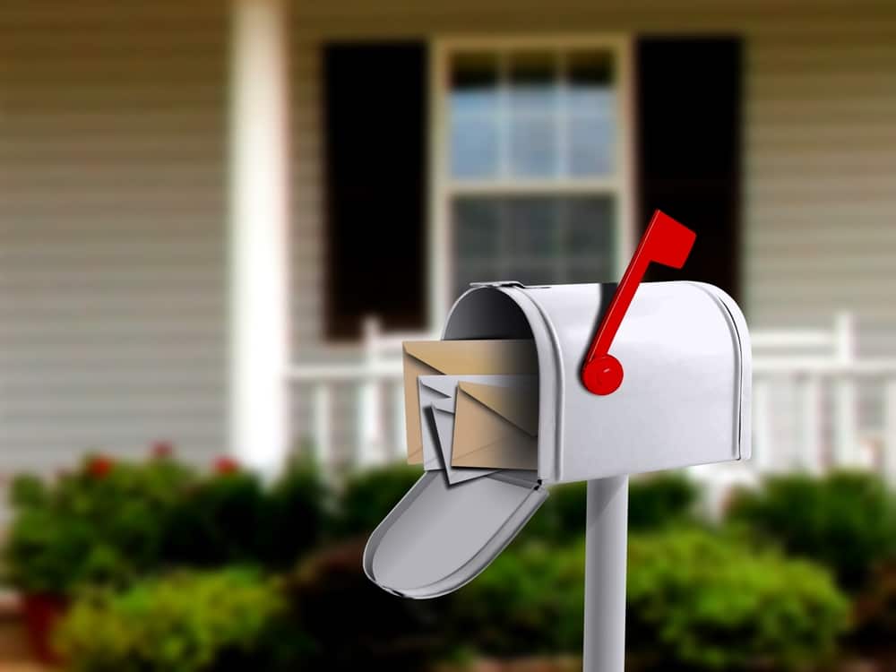 An open mailbox in front of a house shows there are letters inside. 
