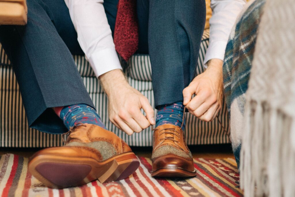 A man is tying his brown leather shoes.