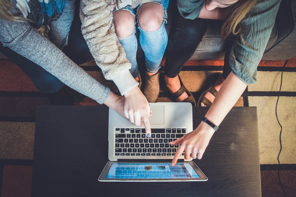 Three young women using a laptop to order pockets with dresses UK from PostFromUS.