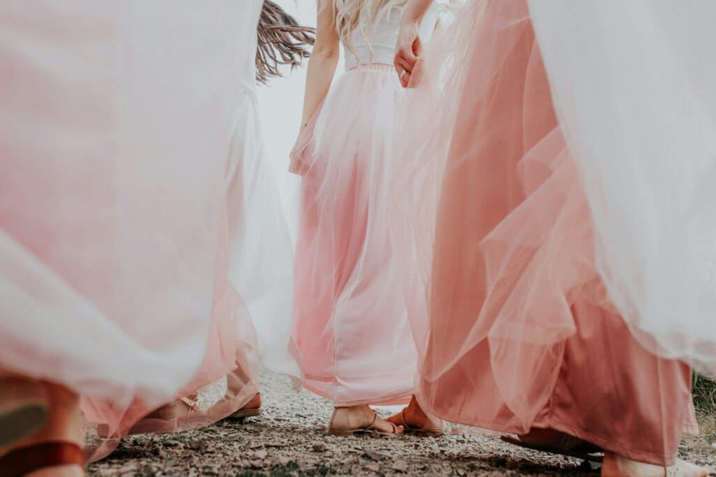 Pink prom dresses with pockets flow in the wind as girls wait outside to enter their prom.