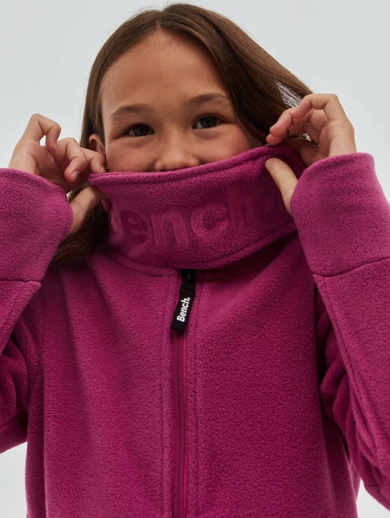 a girl is modelling a pink childrens hoodie with thumb holes by bench