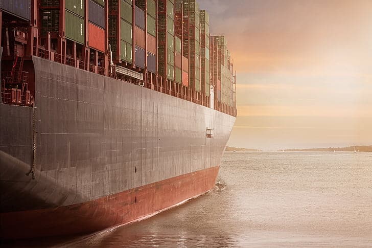 A freight shipping carrier for shipping electronics is on the sea during sunset.