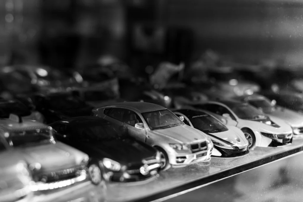 a close up of a model car collection in greyscale. they cars are placed on a shelf.