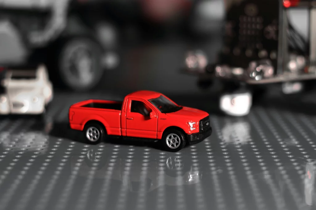 Un camión rojo en una colección de modelos de automóviles en escala de grises.