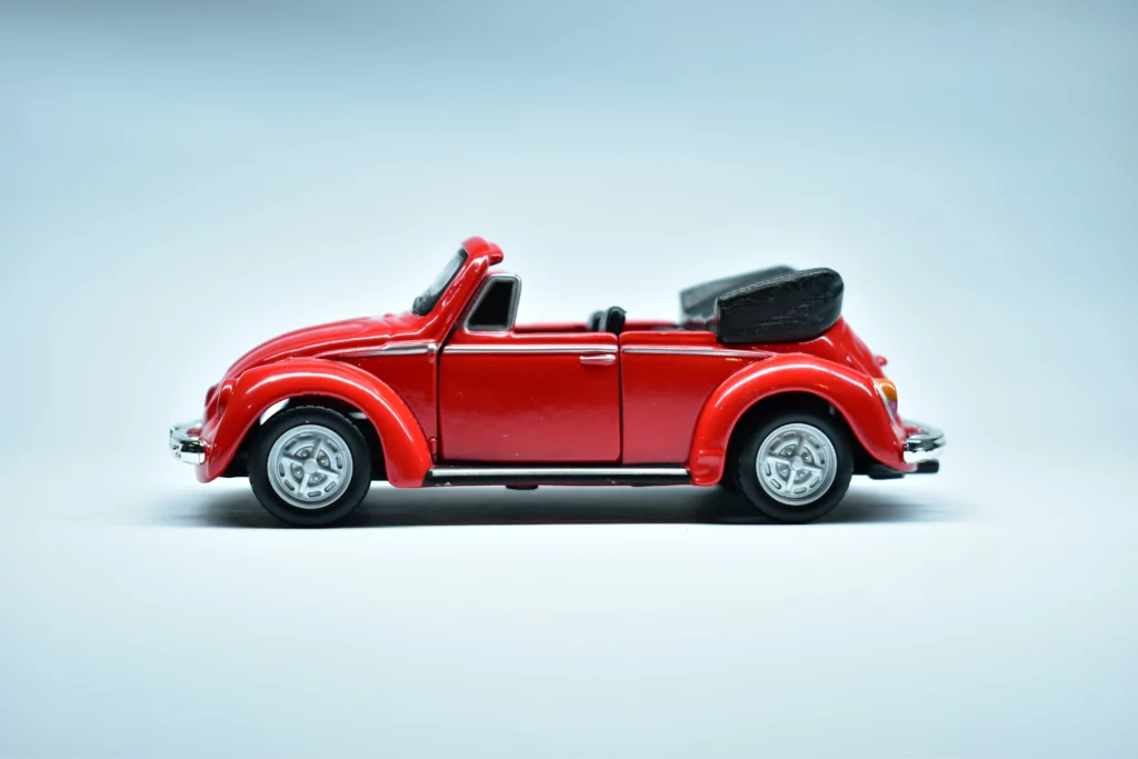Un clásico convertible rojo de una colección de modelos de coches delante de un fondo azul.