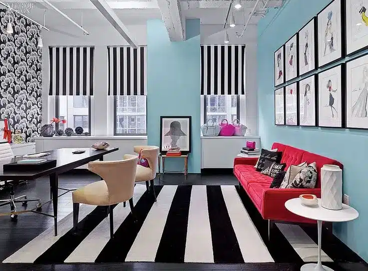Kate Spade home decor. This living room has light blue walls, a hot pink couch, and a black and white striped rug. Accents like this Kate Spade rug make great American gift ideas for families.