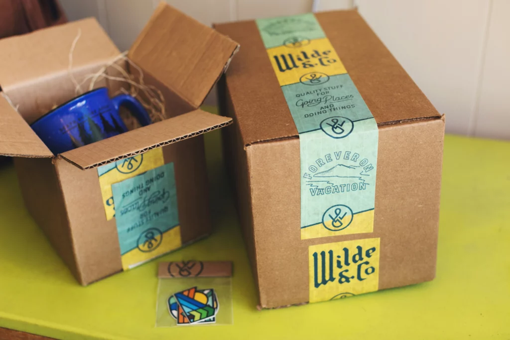 Subscription boxes are on a yellow table. One is opened. American gift ideas can be as simple as a prepackaged box like this.