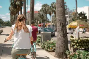 The back view of a woman riding a bike down an island road.