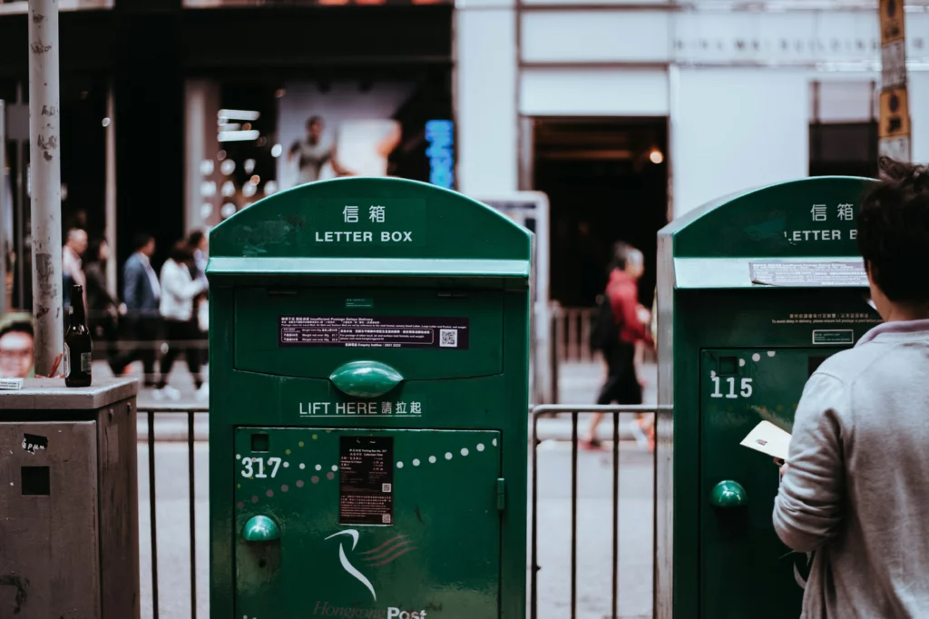 Two green letter boxes on a street.