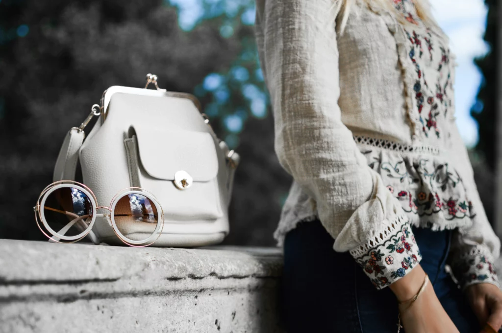 A woman is posing with a white blouse and matching white leather purse. Acquire a unique office-friendly wardrobe by buying from America on eBay with PostFromUS.