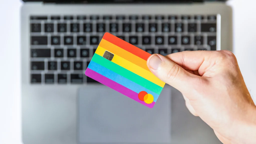 Alguien está mirando su tarjeta de crédito, con su portátil al fondo. Probablemente están reflexionando sobre el aumento de los gastos de envío al comprar desde Estados Unidos en eBay.